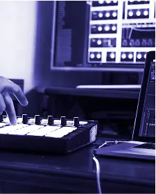 Mano che utilizza un controller MIDI con laptop e monitor