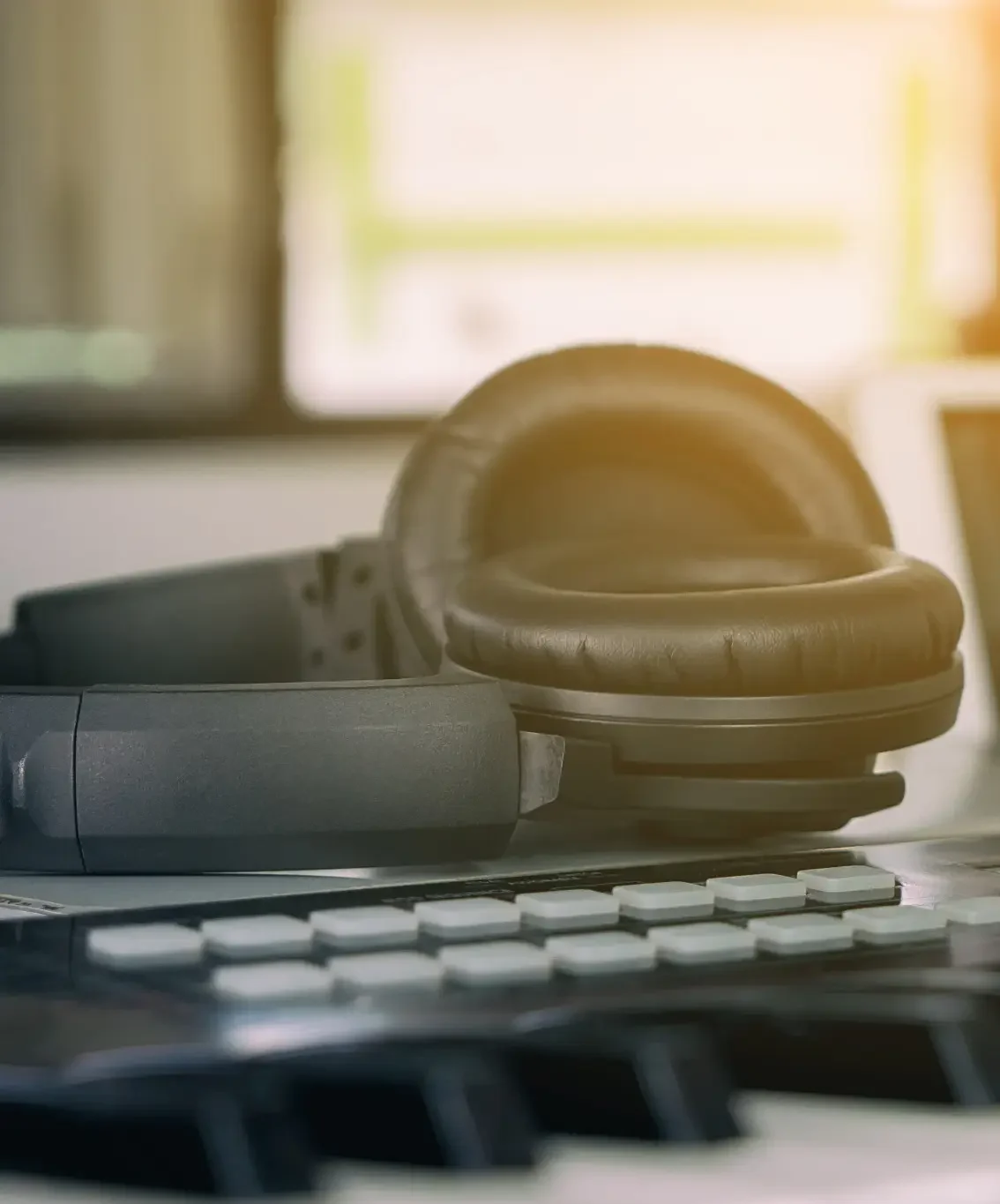 Cuffie appoggiate su una tastiera MIDI in uno studio domestico