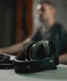 Cuffie appoggiate su un tavolo da studio con persona sfocata sullo sfondo