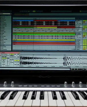 Monitor con Digital Audio Workstation e tastiera MIDI in primo piano