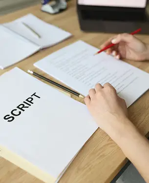 Persona che scrive e corregge uno script su fogli stampati